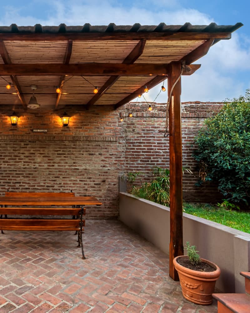 A timber pergola over a brick patio with seating